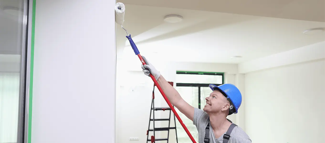 Professional interior painting services in Dubai with a skilled painter using a roller to paint residential ceiling and walls.